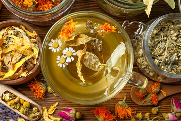 Freshly brewed tea and dried herbs on wooden table, flat lay
