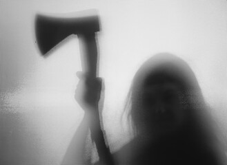 Woman killer with an axe in his hand. Creepy background