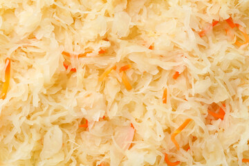 Tasty fermented cabbage with carrot as background, top view