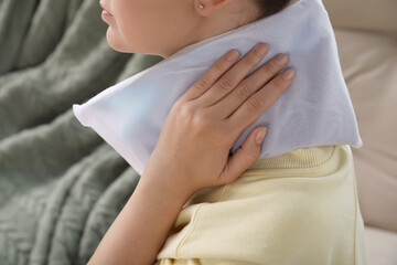 Woman using heating pad at home, closeup