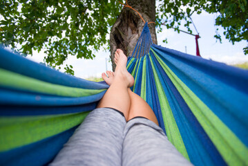 Wypoczynek na hamaku pod drzewem jest dobrym sposobem na relaks w ciepłe dni. - obrazy, fototapety, plakaty