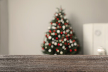 Empty wooden table in room with beautiful Christmas tree. Space for design