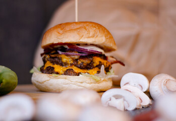 Burger w artystycznej kompozycji z frytkami i batatami oraz cebulą pieczarkami. Burgerownia - zdjęcie świeżego, apetycznego burgera