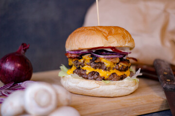 Burger w artystycznej kompozycji z frytkami i batatami oraz cebulą pieczarkami. Burgerownia - zdjęcie świeżego, apetycznego burgera