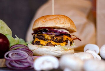 Burger w artystycznej kompozycji z frytkami i batatami oraz cebulą pieczarkami. Burgerownia - zdjęcie świeżego, apetycznego burgera