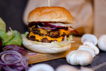 Burger w artystycznej kompozycji z frytkami i batatami oraz cebulą pieczarkami. Burgerownia - zdjęcie świeżego, apetycznego burgera