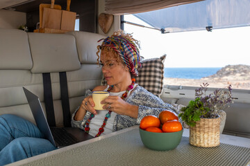 One independent woman laying and working inside a camper van with laptop and connection. Free...