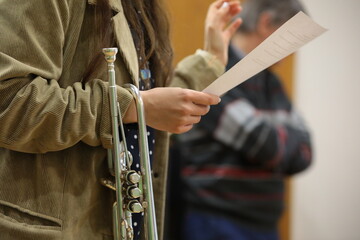 Woman musician student in velvet coat with musical instrument trumpet hanging on hand reads white...