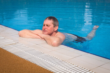 Senior adult swims in the pool. The concept of a healthy active lifestyle in old age