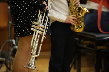 Obraz premium A woman with a trumpet in her hand with a little boy playing a musical instrument saxophone at a lesson in a class a silver horn close-up
