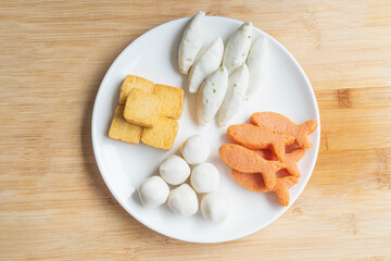 assorted fish meat ball on white bowl on wooden background. top view. copy space of text
