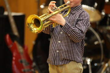 Musician a little boy plays the trumpet concert standing alone on stage in a musical atmosphere...