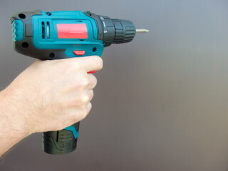 Hand 's man with screwdriver. The worker using an electric drill screwdriver, close-up. Concept of repair and construction services.