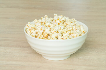 popcorn in bowl on wooden table. copy space for text