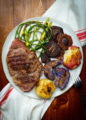 Grilled Delmonico steak with garlic scapes, smashed potatoes and shiitake mushrooms