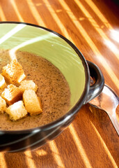 mushroom cream soup with croutons on wooden table Top view sun rays