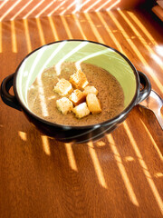 mushroom cream soup with croutons on wooden table Top view sun rays