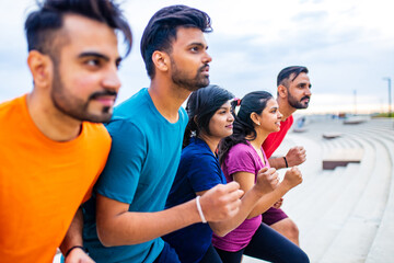 four indian people warming up outdoors in sport wear morning time urban
