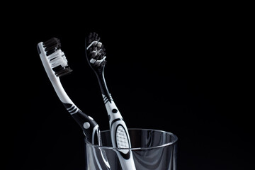 Two toothbrushes in a glass with copy space on black