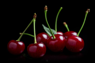 Red cherry berries on a black background with mirror. Three cherries