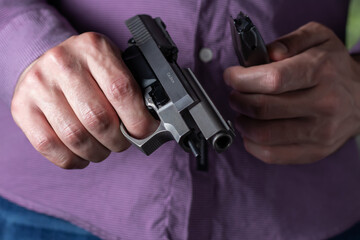 A man holds an empty pistol and clip in his hands