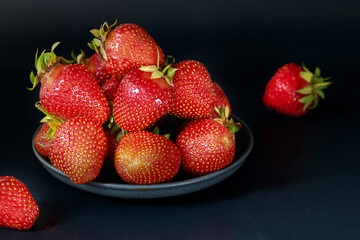 Ripe strawberries on a crunchy dish on a black background.