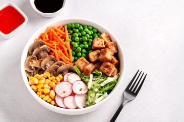 Vegan buddha bowl with tofu, colorful vegetables on base of brown rice.