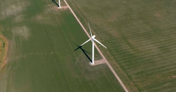 Zoom in aerial view of Single Wind Farm Tower on green agriculture field