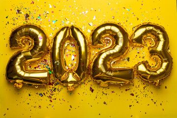 2023 Happy New Year concept from golden foil balloons and confetti