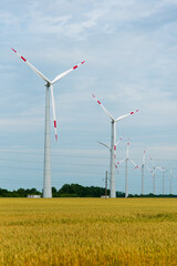 Wind generators in a field of wheat. Ecology. Power engineering. Summer 2022. Alternative energy.