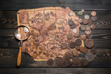 Metal detector, ancient coins and old treasure map on the table top view background. Treasure hunting concept.