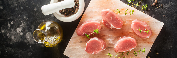 Raw Steak Ribeye on Himalayan pink salt block on dark  background. Top view. Banner