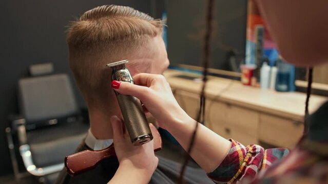 Barbershop: woman hairdresser cuts man's hair with a razor