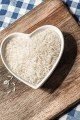 long white rice in a shaped plate in the shape of a heart on a wooden background
