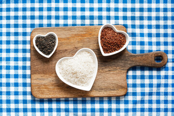 assorted rice set of three plates in the shape of a heart, dishes on a wooden cutting board on a tablecloth