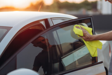 Close up view of a man detailing polishing gray car with a rag. Self-service sink