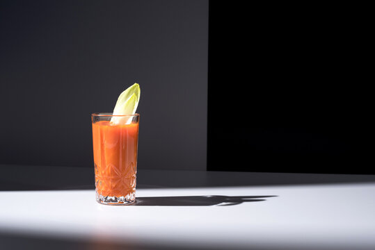 Vaso de jugo de zanahoria con hojas de endibia sobre fondo oscuro