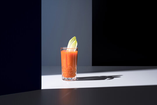 Vaso de jugo de zanahoria con hojas de endibia sobre fondo oscuro