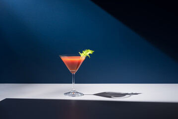 Coctel Bloody Mary decorado con hoja de apio sobre fondo azul	