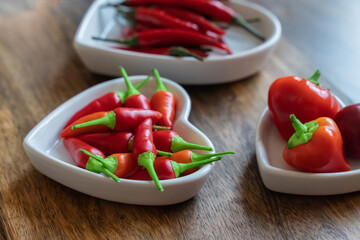 hot assorted red peppers in a white plate on a wooden background selective focus
