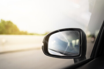 Vehicle side mirror while vehicle moving on the highway with copyspace. Safety driving concept.