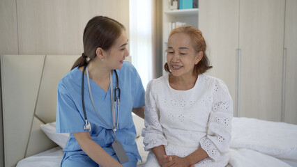 Fototapeta premium Asian doctor giving an advice and explaining to elder female patient with empathy.
