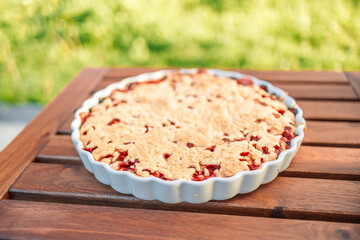 Fresh homemade strawberry cake on a wooden table in the garden. Copy space.