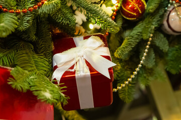 red giftbox with ribbon and bow, small box on the background of the Christmas tree