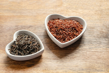 red and black rice long grains in a heart shaped plate on wooden background