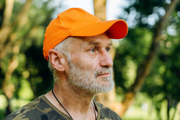 Portrait of sad stressed senior man in orange cap outdoors. Mature man feeling frustrated, lost in...