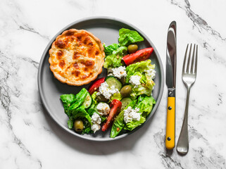 Delicious lunch - mini canned tuna, mozzarella quiche and Greek salad on a light background, top view
