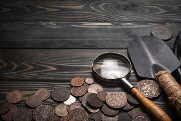 Recreational metal detector and ancient coins on the wooden table background with copy space....