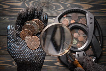 Obraz na płótnie Canvas Hand full of old coins and recreational metal detecor. Treasure hunting concept background.