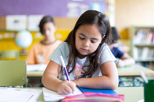 Caucasian little girl doing homework at school. Concept of learning, education and development in children.